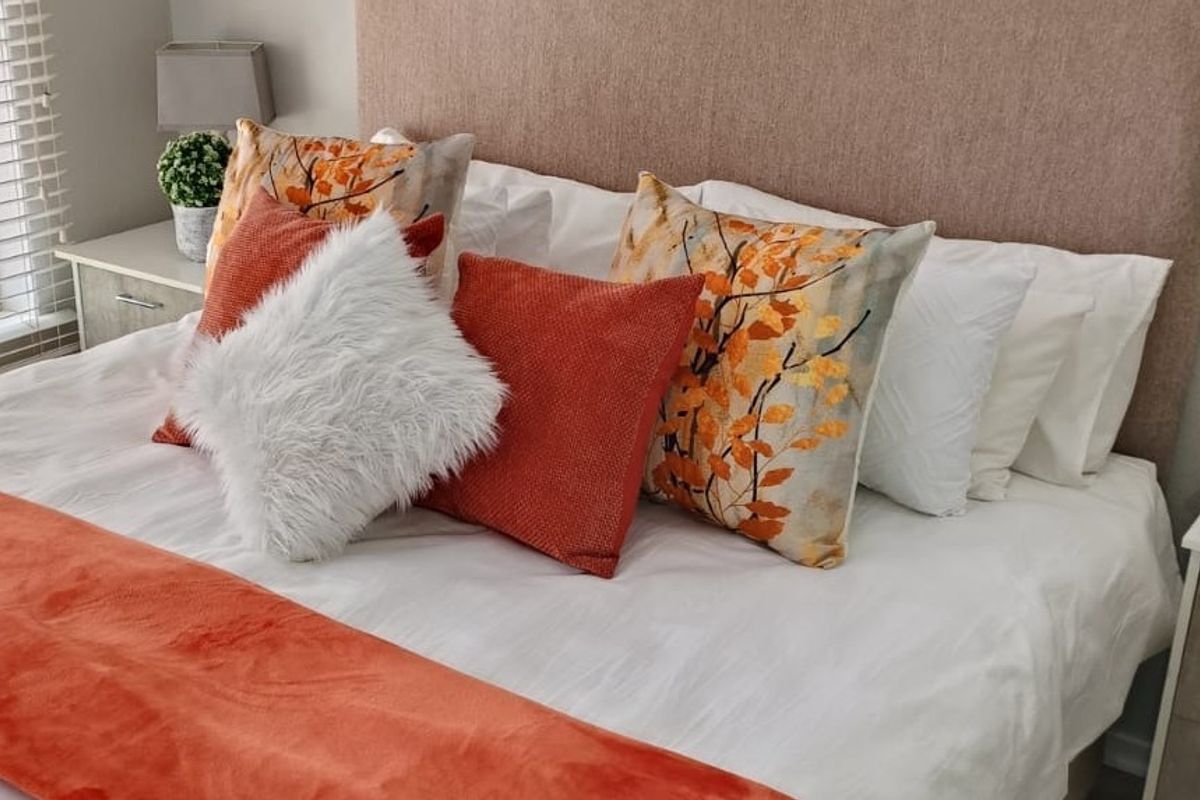 A well-maintained bedroom featuring a neutral upholstered headboard and venetian blinds, providing a clean and comfortable sleeping space.