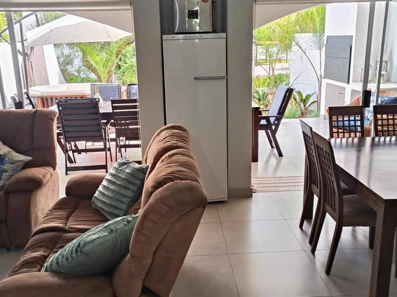 Open plan living and dining area featuring tiled flooring and seamless flow to an outdoor patio with a built-in braai.