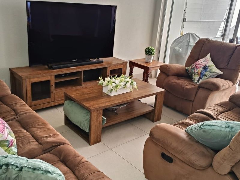 A comfortable living room featuring tiled flooring and a large sliding glass door providing access to the outdoor patio area.