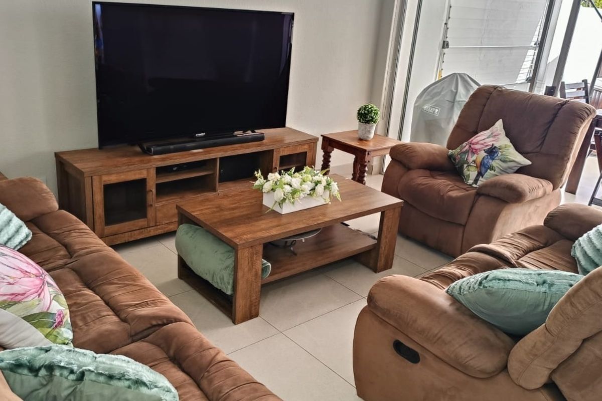 A comfortable living room featuring tiled flooring and a large sliding glass door providing access to the outdoor patio area.