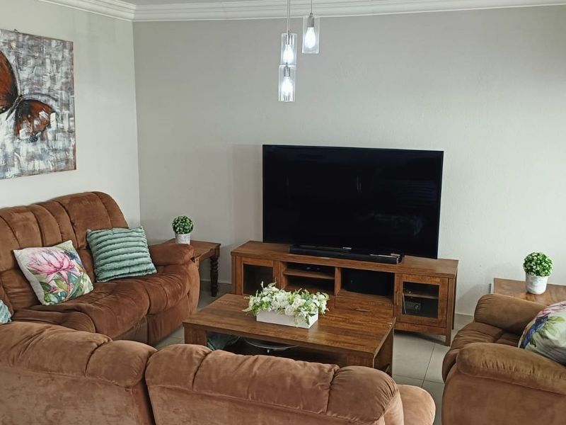 A comfortable living room featuring neutral wall tones, tiled flooring, and decorative pendant lighting, providing a functional and well-maintained space for relaxation.