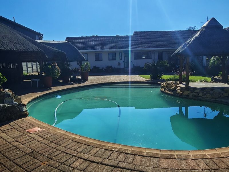 Outdoor pool area featuring a swimming pool, paved surround, and a thatched lapa, perfect for entertaining.