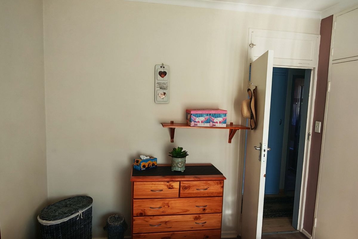 A bedroom featuring a built-in wardrobe with white cabinetry and a standard interior door leading to an adjacent space.