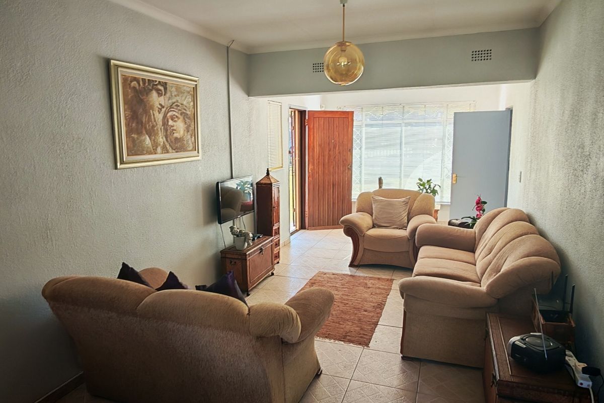 A functional living room featuring tiled flooring and natural light access through a secure entrance door.