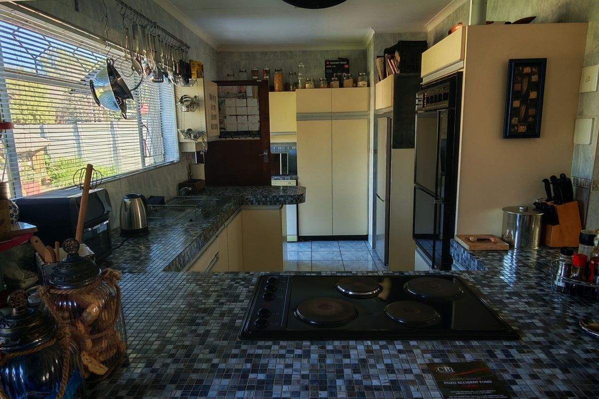 A functional kitchen featuring tiled countertops, built-in cabinetry, an integrated oven, and an electric hob, offering a practical layout with ample workspace.