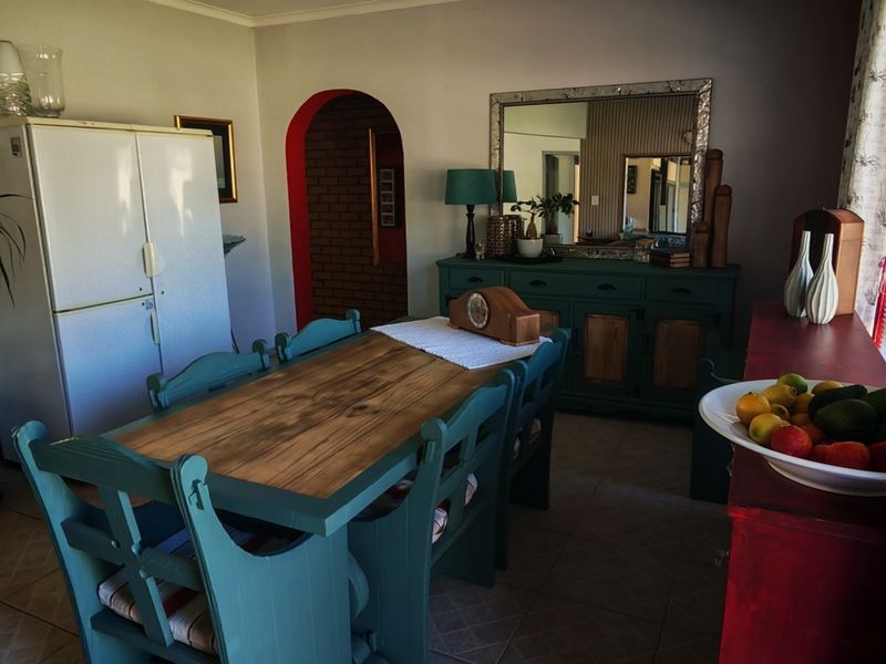 A dining room featuring tiled flooring and a distinctive arched doorway leading to an adjacent space with exposed brickwork.