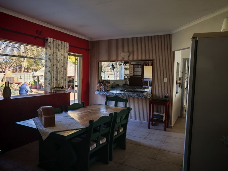 Open plan dining area featuring tiled flooring and a convenient serving hatch connecting to the kitchen, with large windows providing natural light.