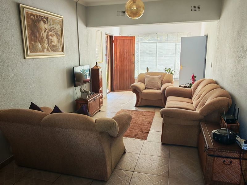 A living room featuring tiled flooring and a timber entrance door, providing a functional and accessible living space.