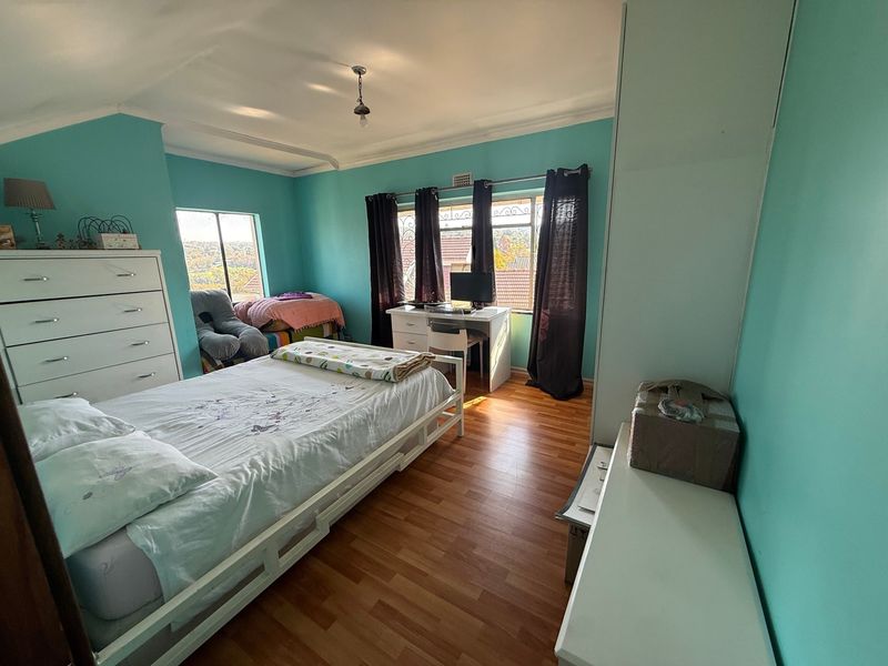 A bedroom featuring laminate flooring, built-in wardrobe storage, and security bars on the windows, offering a functional living space.