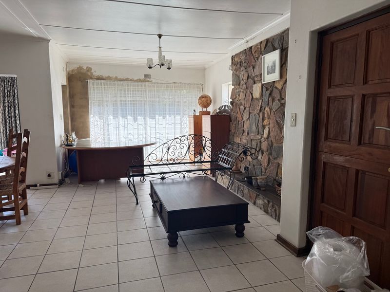 Living room featuring a prominent stone accent wall, tiled flooring, and direct access to the garden area.