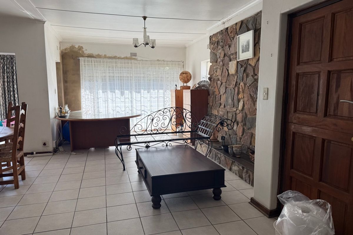 Living room featuring a prominent stone accent wall, tiled flooring, and direct access to the garden area.