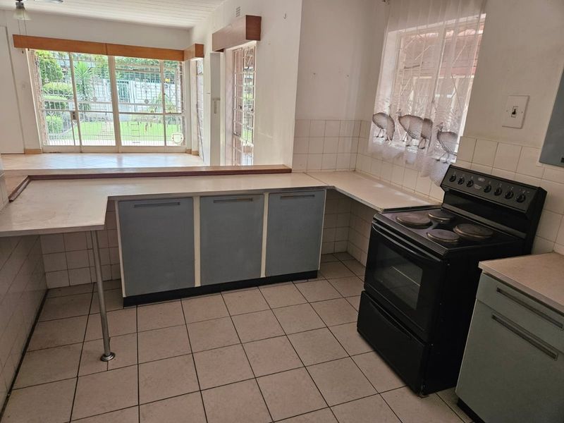 Functional kitchen featuring tiled flooring, built-in cabinetry, a breakfast bar, and a freestanding stove, with direct access to the adjacent living area.