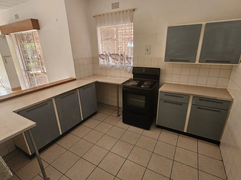 A dated kitchen featuring original cabinetry, laminate countertops, and ceramic tile flooring, offering a blank canvas for a modern renovation.