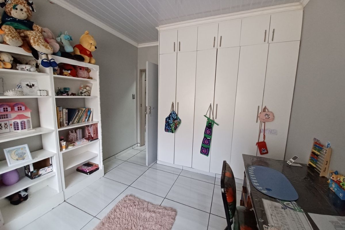 A bedroom featuring white built-in cupboards, tiled flooring, and a clean ceiling finish, providing ample storage space.