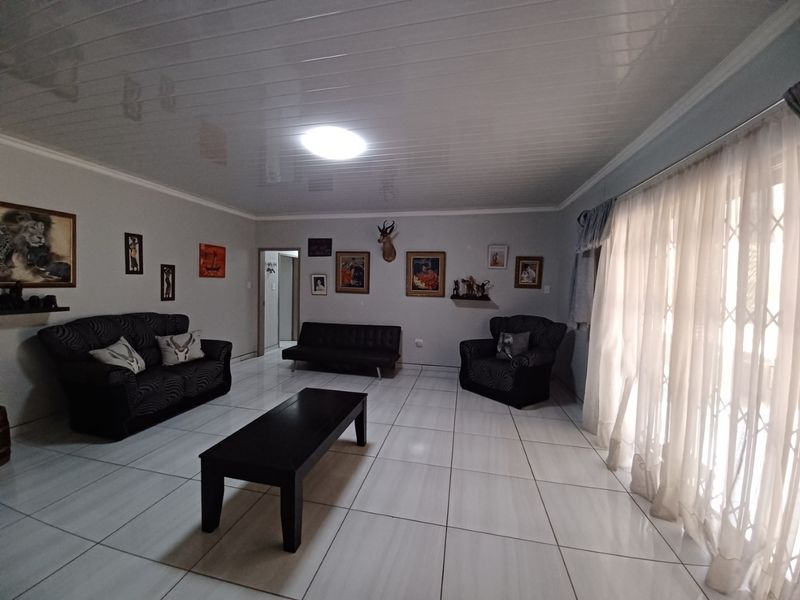 Spacious living room featuring large format floor tiles and a glossy ceiling finish, with direct access to the exterior through a sliding door.