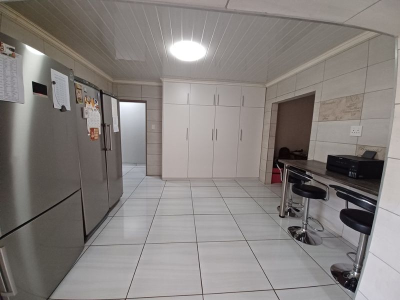 A functional kitchen area featuring tiled flooring, extensive built-in cabinetry, and a breakfast bar counter, providing ample storage and workspace.