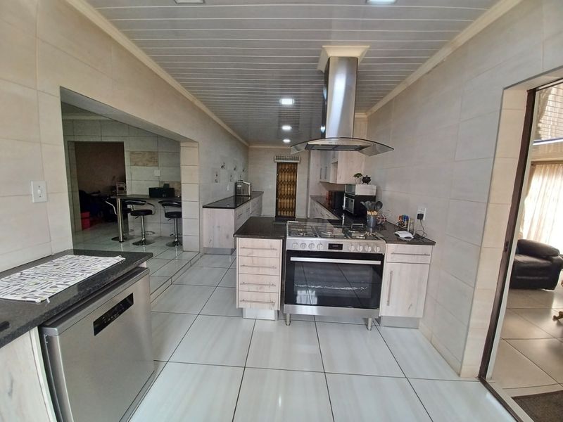 Modern kitchen featuring light wood cabinetry, granite countertops, stainless steel appliances, and tiled flooring with a clean, functional layout.