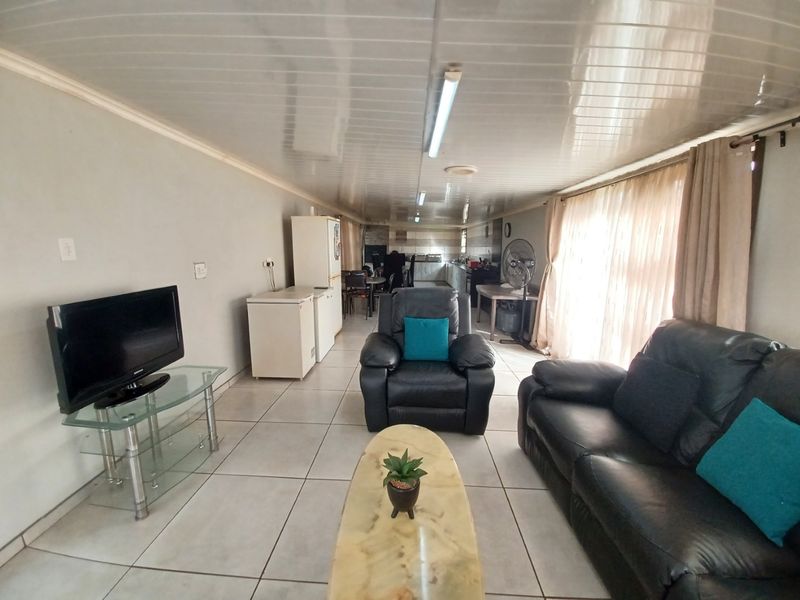 Open-plan living and kitchen area featuring tiled flooring and PVC ceiling panels, providing a functional and connected living space.