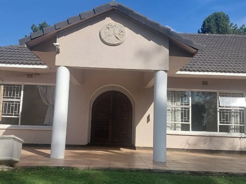 Front facade of a farm-style residence featuring a covered patio, arched entrance, and classic architectural detailing with security-fitted windows.