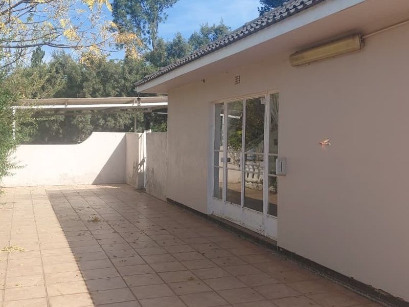 A paved outdoor patio area featuring sliding glass door access and a boundary wall, offering a functional space for outdoor living.