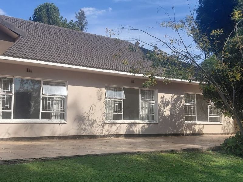 Rear view of the farmhouse featuring a tiled patio, security bars on windows, and a pitched tiled roof overlooking the garden.