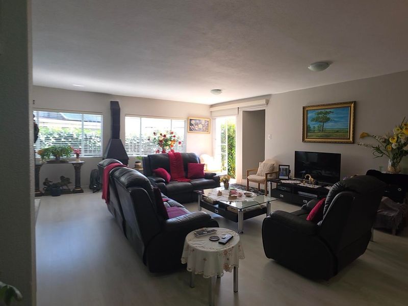 Spacious living room featuring laminate flooring, a freestanding fireplace, and access to the outdoor area through a sliding door.