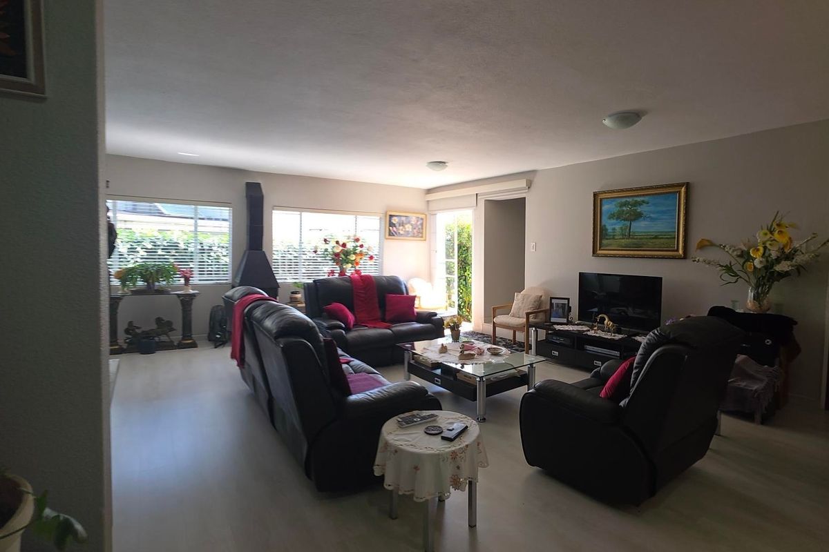 Spacious living room featuring laminate flooring, a freestanding fireplace, and access to the outdoor area through a sliding door.