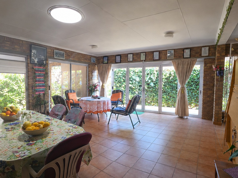 Spacious living area featuring exposed brick walls, tiled flooring, and multiple sliding glass doors providing abundant natural light and garden access.