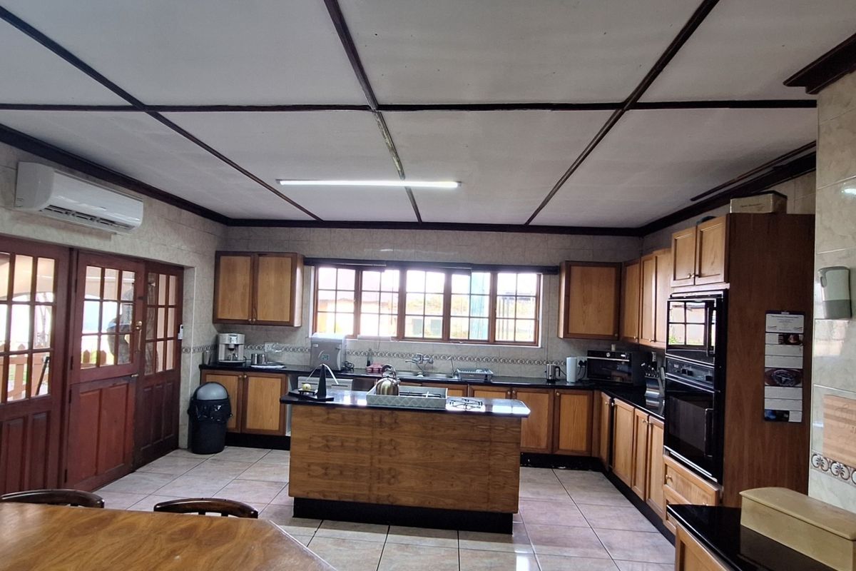 Spacious kitchen featuring wooden cabinetry, granite countertops, a central island, and built-in double oven, offering a functional layout with tiled flooring.