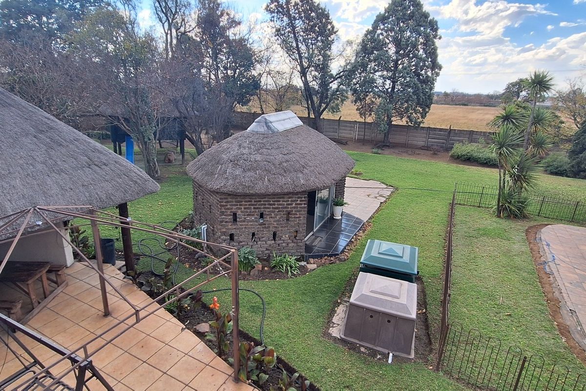 Aerial view of the small holding property featuring a thatched-roof structure, a swimming pool, and a spacious garden area.