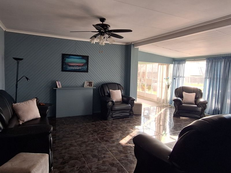 Spacious living room featuring tiled flooring, a ceiling fan, and large sliding glass doors that provide ample natural light and access to the outdoors.
