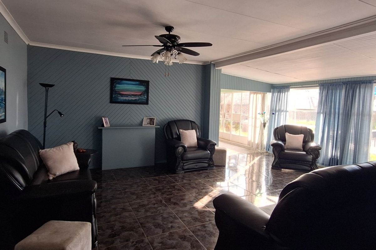 Spacious living room featuring tiled flooring, a ceiling fan, and large sliding glass doors that provide ample natural light and access to the outdoors.