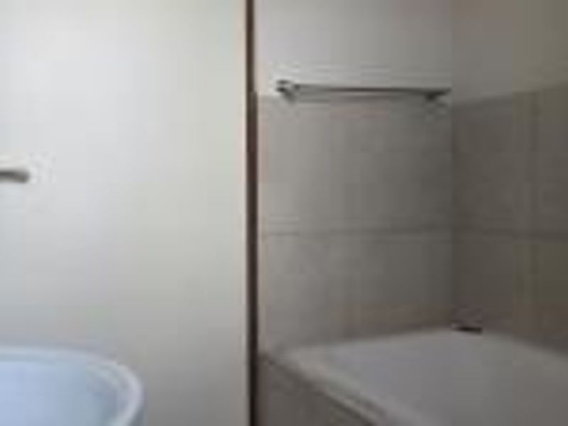 A functional bathroom featuring a bathtub, basin, and tiled wall finishes with a mounted towel rail.