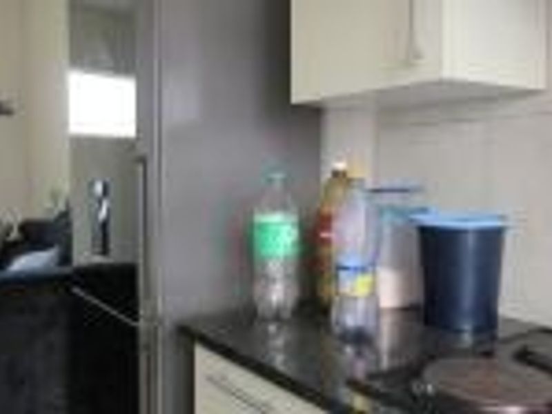 A compact kitchen area featuring built-in cabinetry, a stone countertop, and an integrated electric hob.