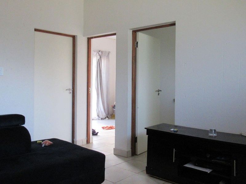 A living area featuring tiled flooring and access to adjacent rooms through internal doorways.