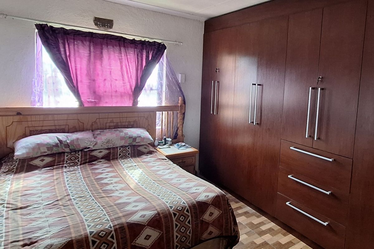 A bedroom featuring extensive built-in wooden cupboards and tiled flooring, offering functional storage space within the home.