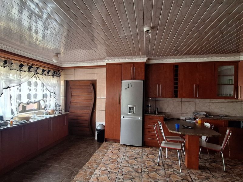 Spacious kitchen featuring extensive wooden cabinetry, laminate countertops, a built-in breakfast nook, and tiled flooring with a PVC ceiling finish.
