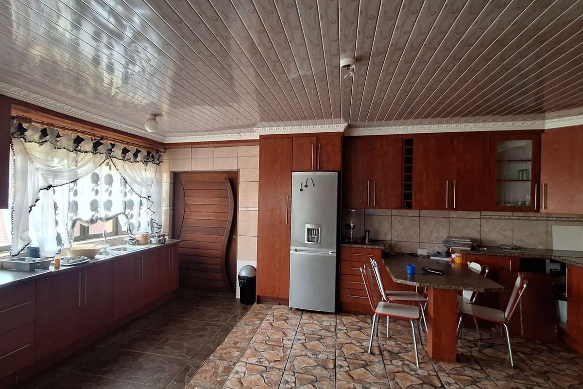 Spacious kitchen featuring extensive wooden cabinetry, laminate countertops, a built-in breakfast nook, and tiled flooring with a PVC ceiling finish.