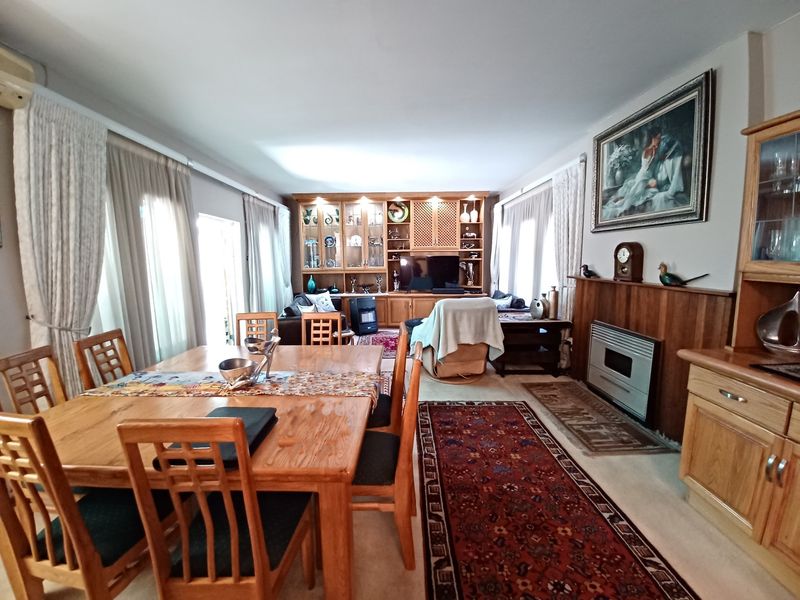 Spacious open-plan living and dining area featuring built-in wooden cabinetry, a gas fireplace with a mantelpiece, and large windows allowing natural light.