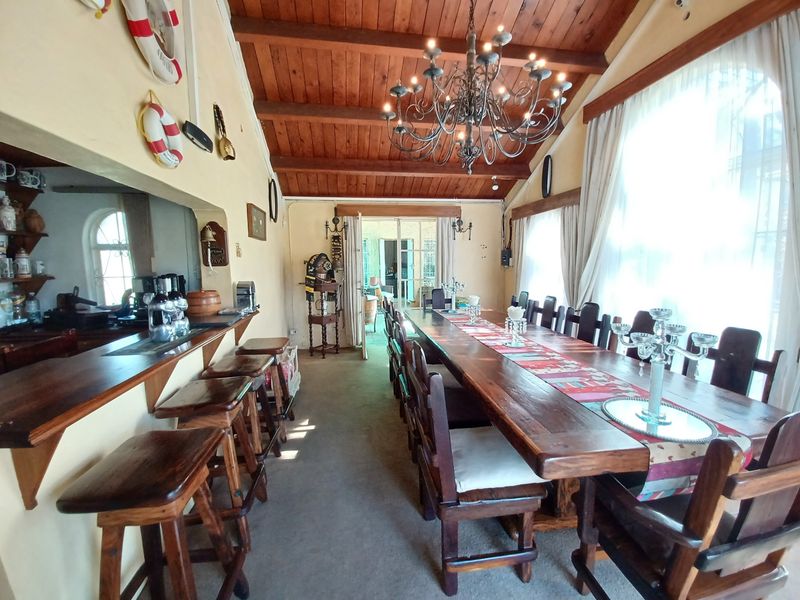 Spacious dining area featuring a high exposed timber beam ceiling, a built-in bar counter, and a classic wrought iron chandelier.