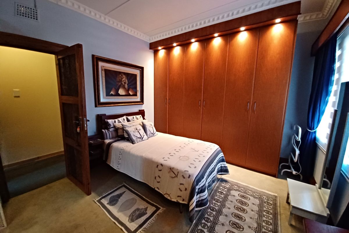A well-maintained bedroom featuring extensive built-in wooden cabinetry with integrated downlighting and classic crown molding details.