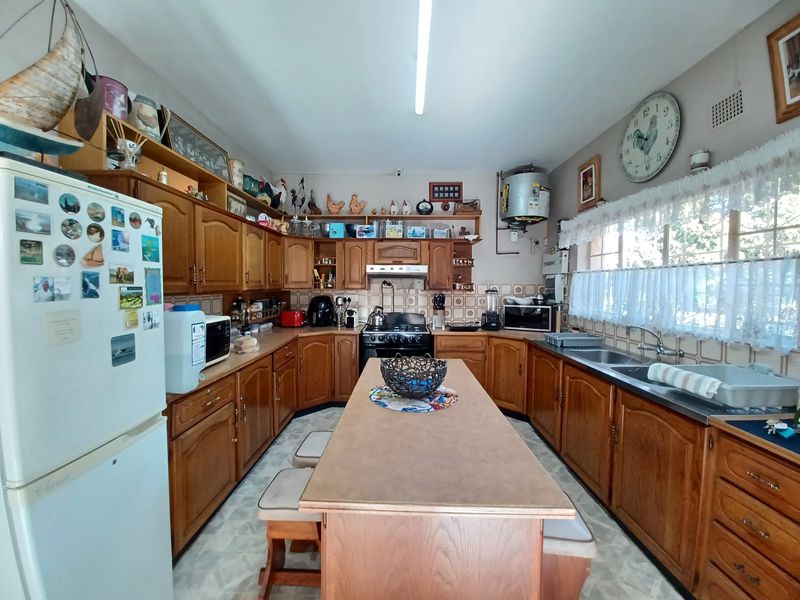 A functional kitchen featuring wooden cabinetry, a central island, double sink, and gas stove, offering a traditional layout with ample storage space.