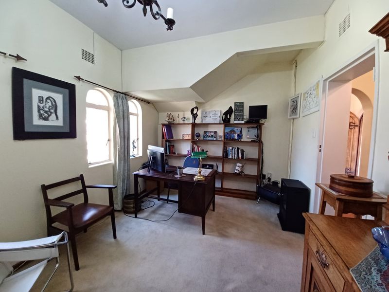 A functional home office featuring built-in shelving, arched windows, and neutral carpeting, providing a quiet space for work or study.