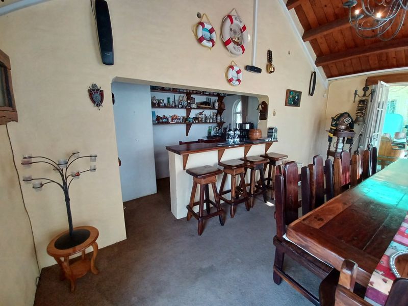 A rustic-style bar area featuring a built-in counter, shelving, and exposed timber ceiling beams, creating a cozy entertainment space.