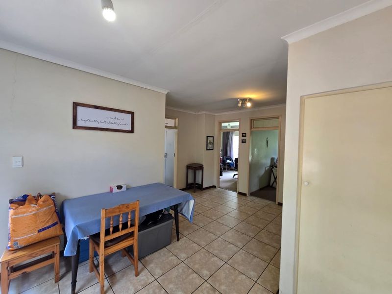 A functional hallway area featuring tiled flooring, coved ceilings, and access to adjacent rooms, showing standard wear and tear.