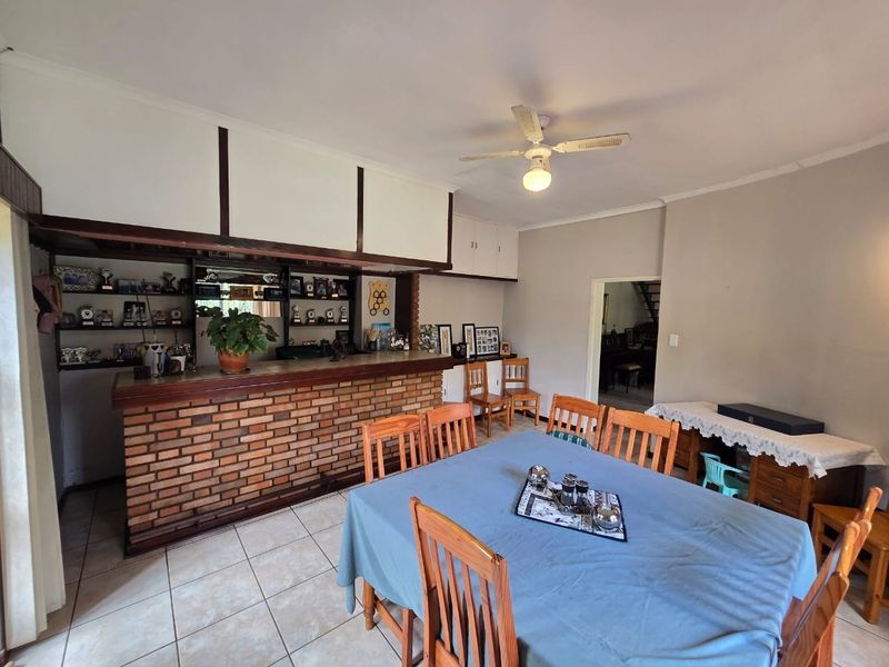 A dedicated bar area featuring a built-in brick counter and integrated shelving, adjacent to a dining space with tiled flooring.