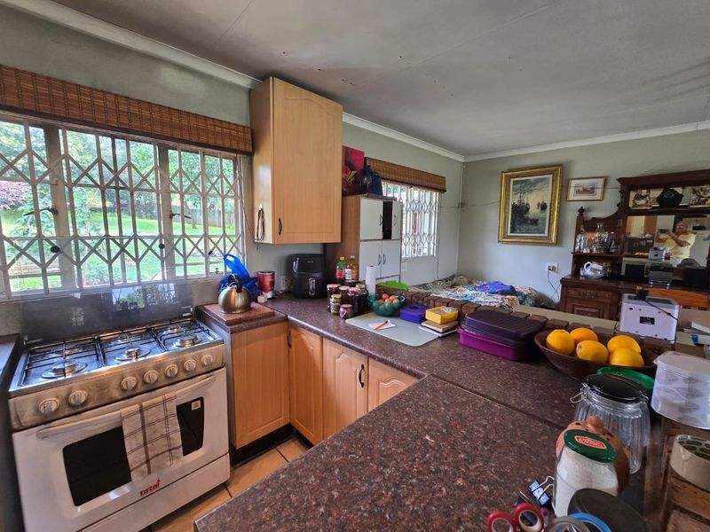 A functional kitchen featuring wooden cabinetry, gas stove, and granite-look laminate countertops with security gates on the windows.