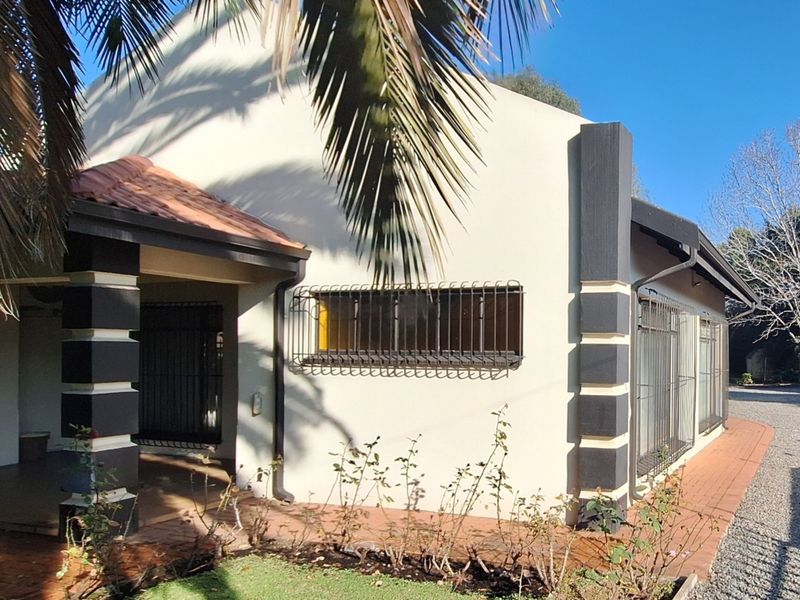 A view of the front facade featuring a covered patio, terracotta roof tiles, and security bars on the windows.