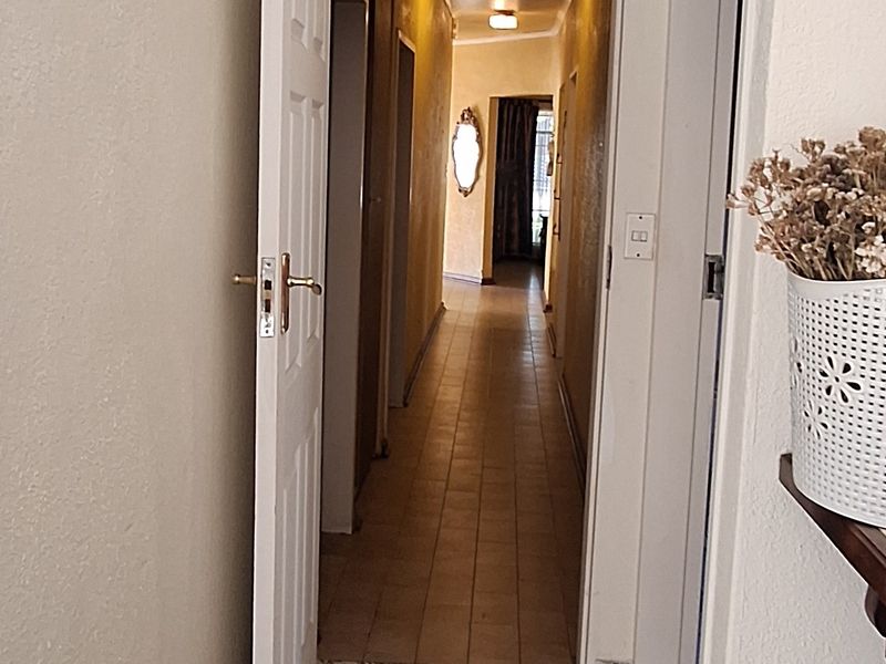 A long, tiled hallway connecting multiple rooms, featuring neutral walls and standard interior doors.