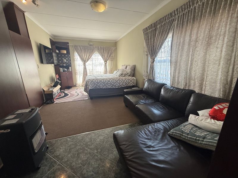 A multi-functional bedroom space featuring a combination of tiled and carpeted flooring, built-in cabinetry, and dual window treatments.